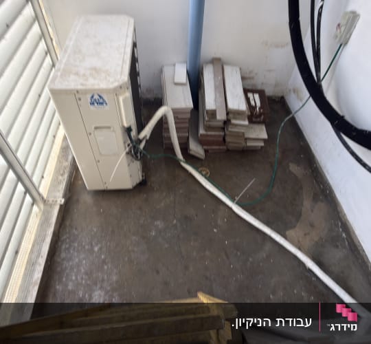 מסתור כביסה מלוכלך עם מעבה מזגן ושאריות אריחי ריצוף